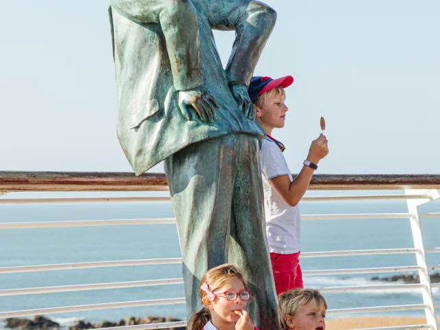 Enfants en famille devant la statue de Monsieur Hulot